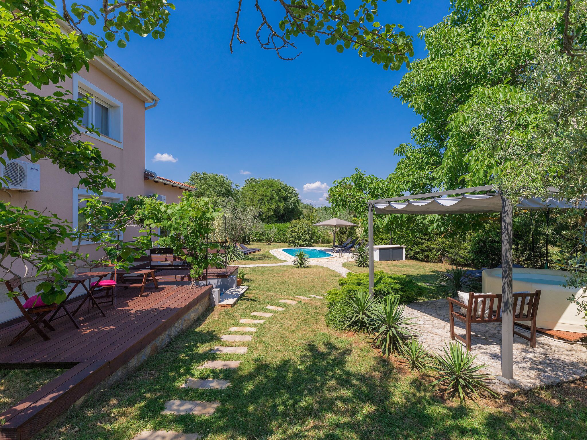Un jardin avec une piscine, du mobilier d’extérieur et une pergola.
