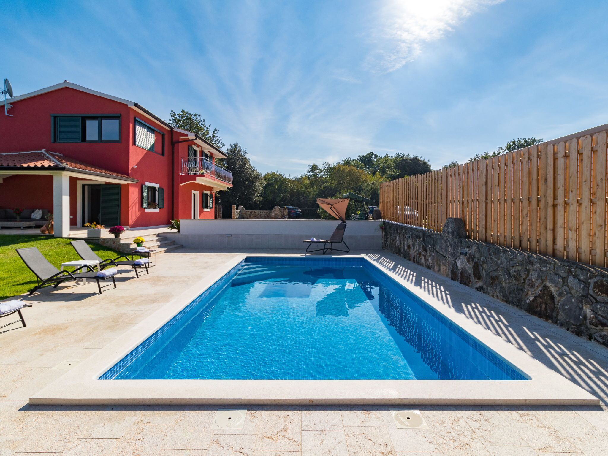 A swimming pool with a red house in the background.