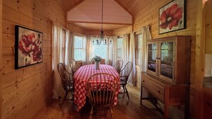 A wooden cabin interior with a dining table set for four, surrounded by chairs.