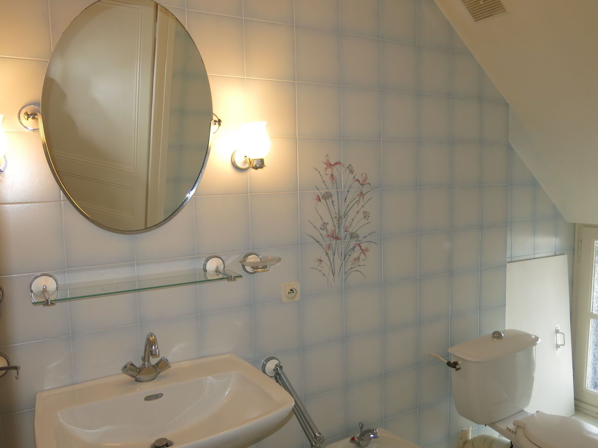 Une salle de bain avec un lavabo, un miroir et des toilettes.