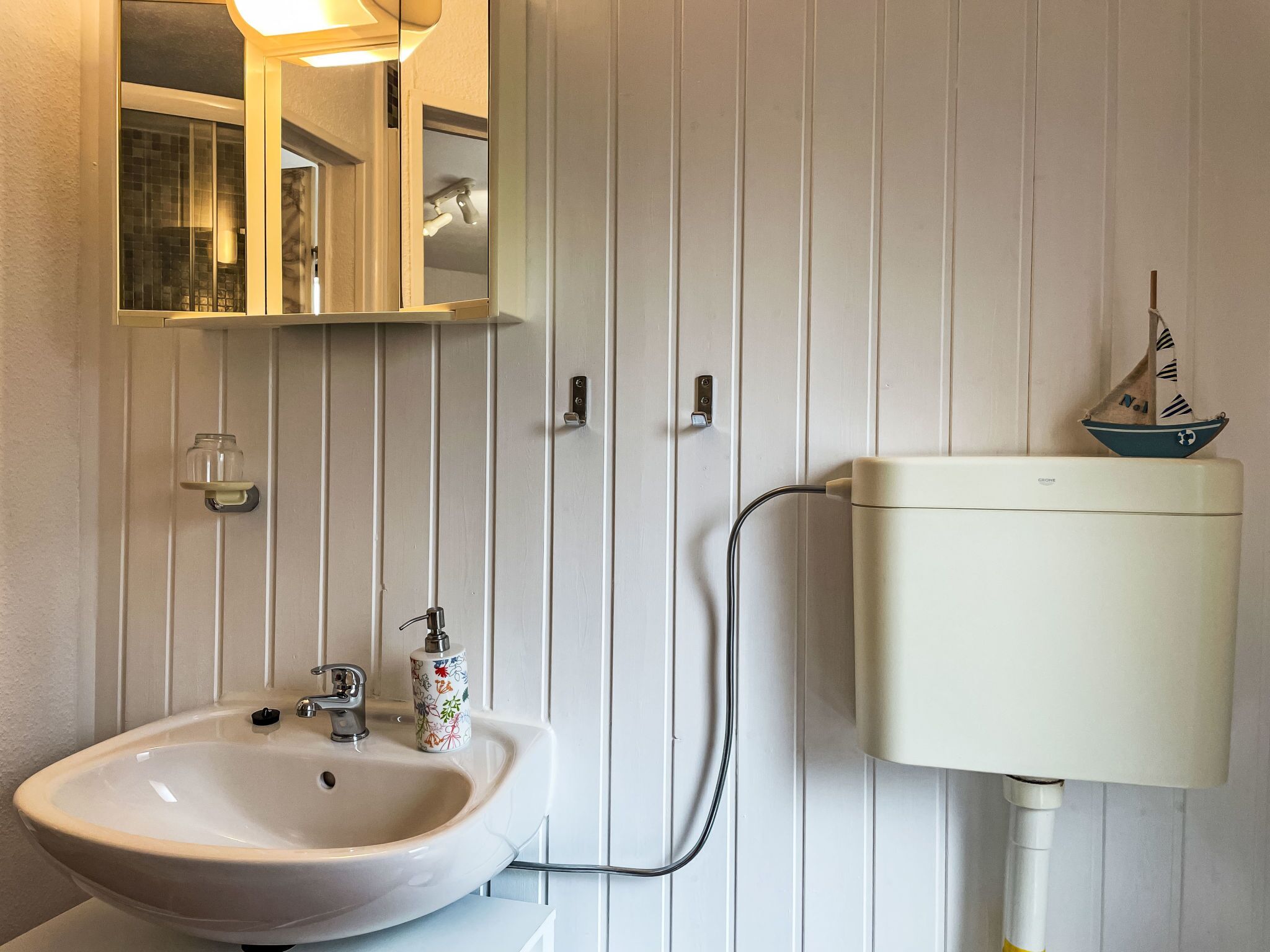 A bathroom with a white sink, a mirror, and a toilet.