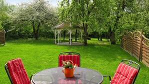 A patio with a round metal table and four red-striped chairs.
