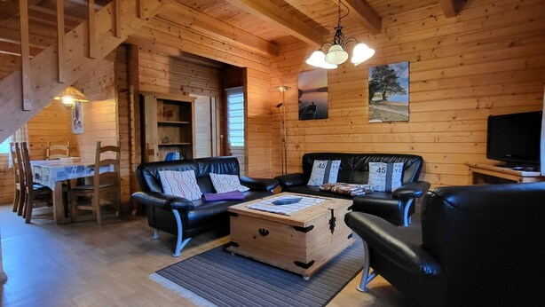 A wooden cabin interior with a dining area, a sofa set, a television, and a staircase. - Zum Stolpseefischer by Interhome (Himmelpfort)