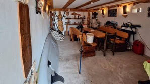 Tunnelmallinen, maalaishenkinen mökin sisustus, jossa on ruokailutila, puiset penkit, pöytä ja kalastusvälineet.