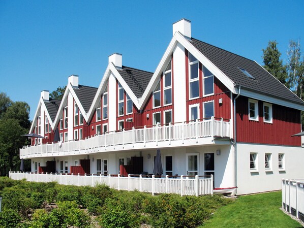 Un grand bâtiment rouge et blanc, doté de nombreux balcons et entouré d’une clôture blanche.