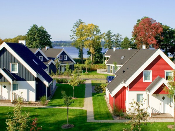 A row of modern houses with a well-maintained lawn and a clear view of the water in the background.