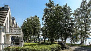 A lakeside property with a large house, a paved pathway, and a view of the lake. - Falster by Interhome (Bad Saarow)