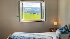 A bedroom with a large window offering a view of a green field and hills. - Mühlenmichelshäusle by Interhome (Hinterzarten)