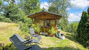 A wooden cabin with a porch, surrounded by lush greenery and trees. - Mühlenmichelshäusle by Interhome (Hinterzarten)