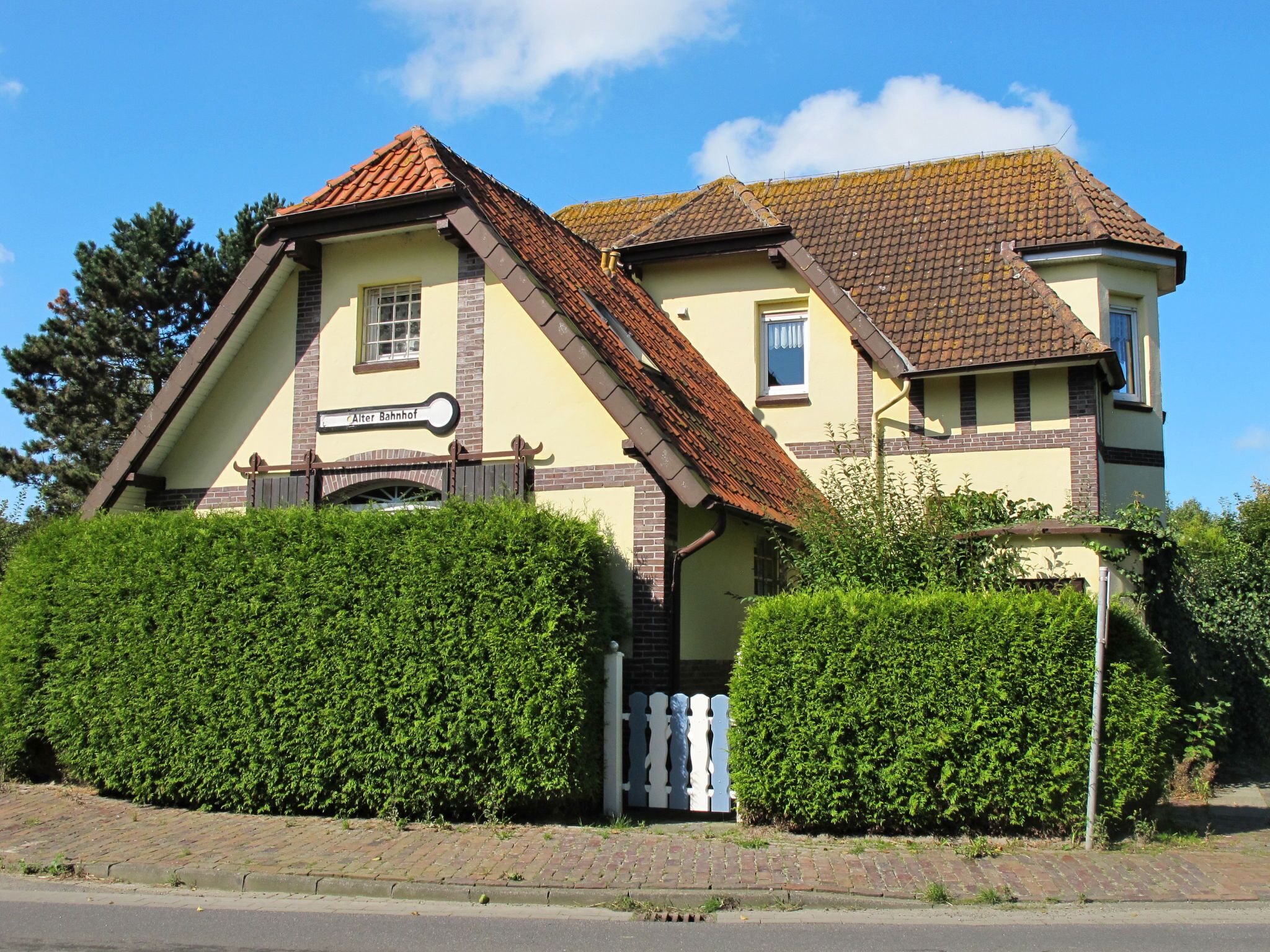 A two-story building with a traditional architectural style, featuring a tiled roof and a sign that reads "Alter Bahnhof."