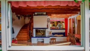 A cozy interior with a wooden staircase, a fireplace, and a dining area with a checkered tablecloth. - Karasova II by Interhome (Dehtáře)