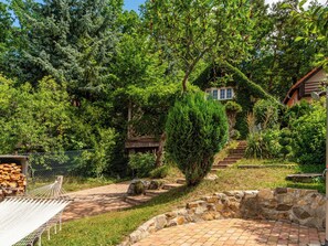 A garden with a hammock, stone wall, and a house partially covered by ivy. - Karasova II by Interhome (Dehtáře)