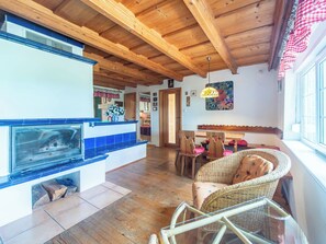 A cozy interior with a fireplace, wooden ceiling, wicker furniture, and a dining area. - Karasova II by Interhome (Dehtáře)