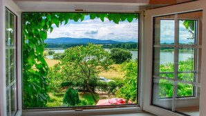 A window with a view of a lake, trees, and distant mountains. - Karasova II by Interhome (Dehtáře)
