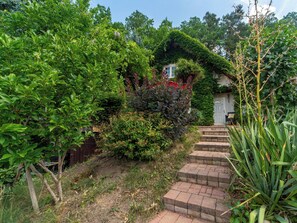A garden with a brick pathway leading to a white door, surrounded by lush greenery and a variety of plants. - Karasova II by Interhome (Dehtáře)