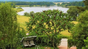 A lakeside view with a swing chair and a covered seating area. - Karasova II by Interhome (Dehtáře)