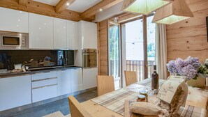 A modern kitchen with white cabinets, stainless steel appliances, and a wooden ceiling. - Nice apartment in Lanzada (Lanzada)