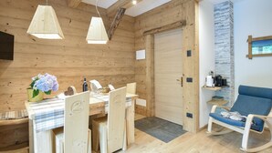 A wooden interior with a dining table, chairs, a blue rocking chair, and pendant lights. - Nice apartment in Lanzada (Lanzada)