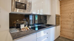 A modern kitchen with stainless steel appliances, a black countertop, and white cabinetry. - Nice apartment in Lanzada (Lanzada)