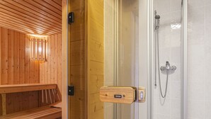 A wooden sauna with a bench, a glass-enclosed shower area with a handheld showerhead, and a control panel. - Vacation home Naulaz by Interhome (Les Crosets)