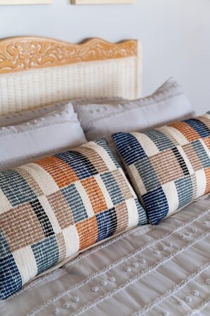A bed with a wooden headboard, multiple pillows, and a quilted bedspread.