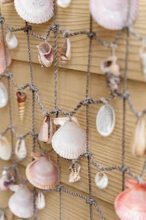 A close-up of a rope netting with various seashells hanging from it.
