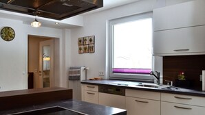 Eine moderne Küche mit schwarzem Arbeitsplatten, weißen Schränken, einem integrierten Geschirrspüler und einem Fenster mit Jalousien.