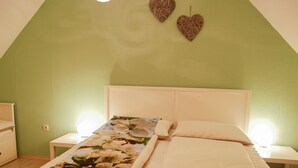Un dormitorio con una cama individual, dos mesitas de noche y una pared verde.