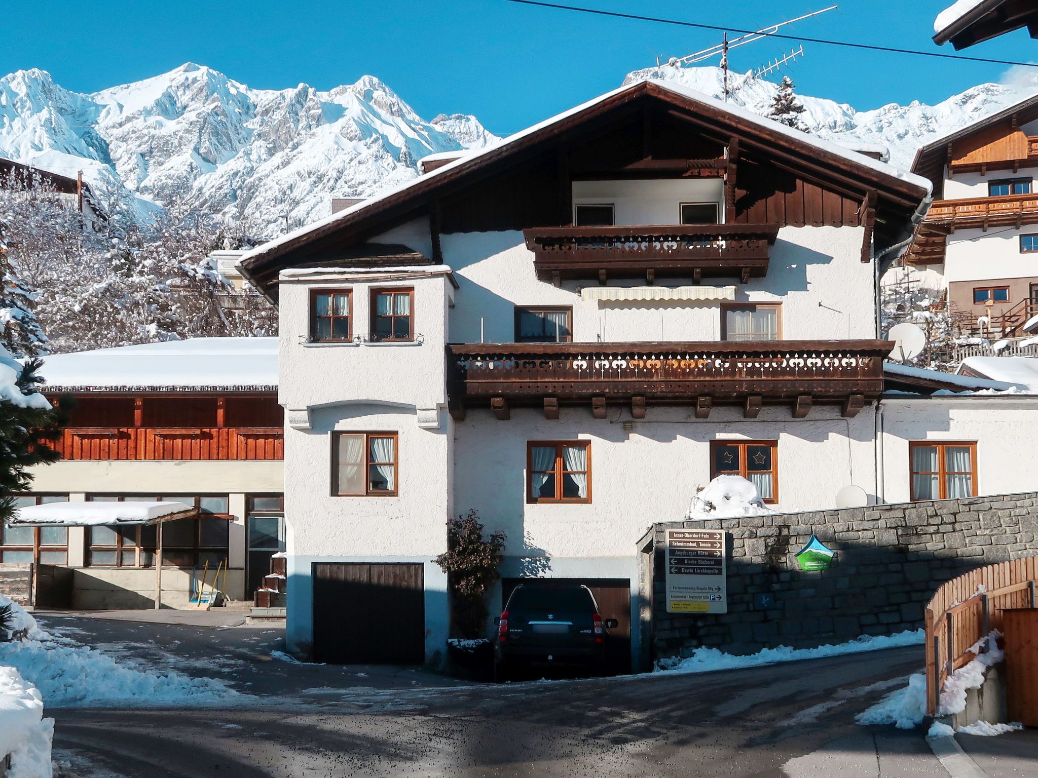 A two-story building with a balcony, a garage, and a sign indicating nearby locations.