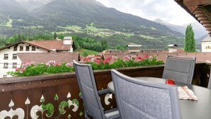 A balcony with a view of a mountainous landscape, including houses and greenery. - Apartment Huber by Interhome (Grins)
