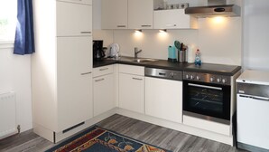 A modern kitchen with white cabinets, a black countertop, a built-in oven, and a dishwasher. - Apartment Huber by Interhome (Grins)