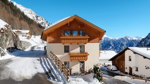 Un chalet di legno a due piani con un balcone, sullo sfondo di una montagna innevata.