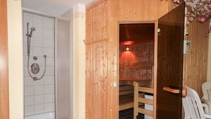 Una sauna in legno con una panca e uno spazio doccia.