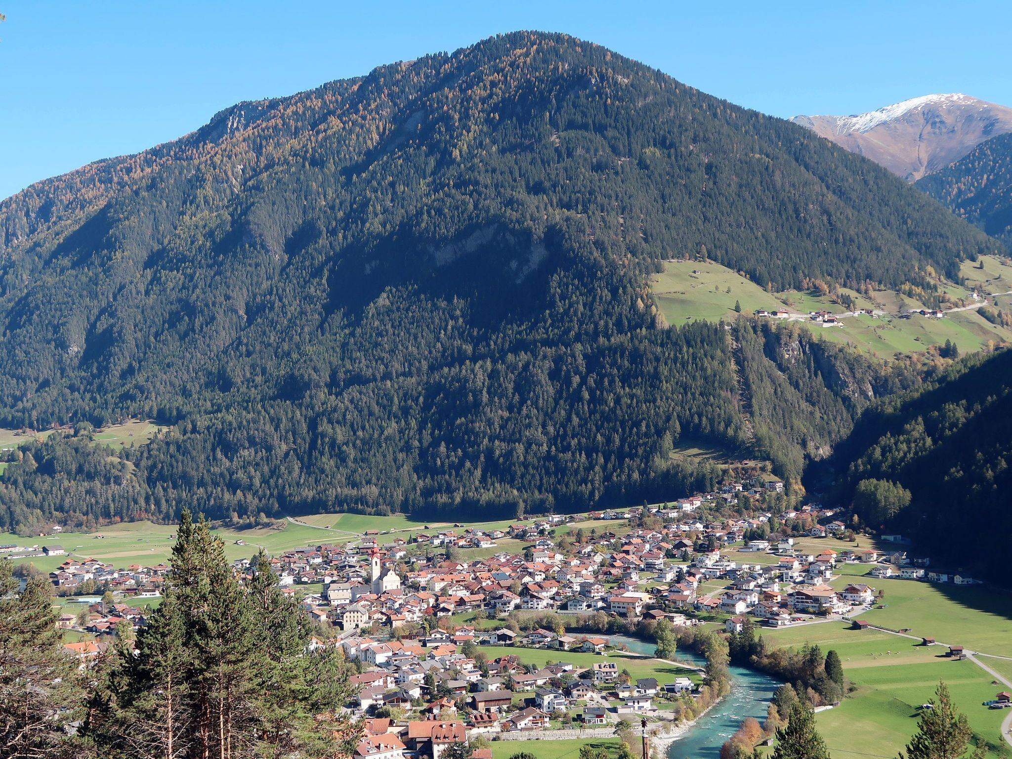 Eine Stadt liegt eingebettet in ein Tal, umgeben von Bergen, durch eine Fluss durchflossen.