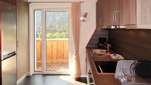 A modern kitchen with a sliding glass door leading to a wooden deck, stainless steel appliances, and a coffee maker.