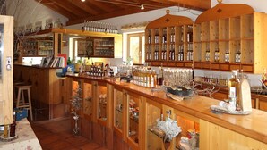 A bar area with wooden shelves stocked with bottles and glasses, a counter with various items, and a rustic interior with exposed wooden beams.