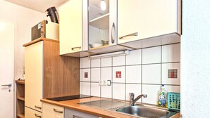 Una cocina compacta con un lavamanos, armarios de madera y un salpicadero de azulejos.