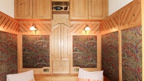 Una habitación con dos camas, paredes de madera y un papel tapiz estampado.