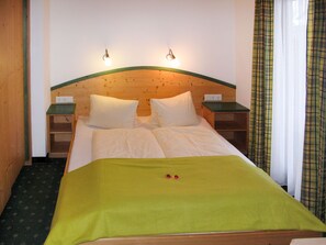 A wooden-framed bed with a green bedspread, two bedside tables, and a wall-mounted light fixture. - Gratzerhof by Interhome (Finkenberg)