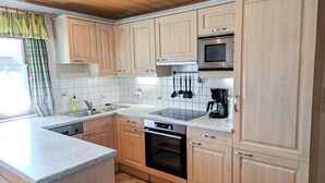 Una cocina con armarios de madera, un microondas de acero inoxidable, un horno y una cafetera.