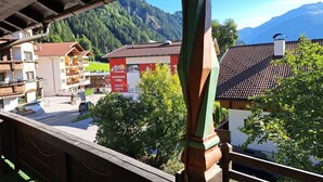 Un pueblo de montaña con edificios de madera tradicionales, un cartel de escuela de snowboard y vistas de las montañas circundantes.