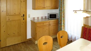 A wooden kitchen with cabinets, a microwave, and a dining area with chairs.