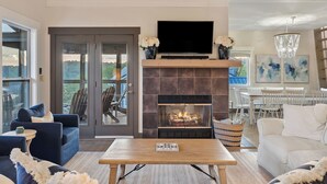 A living room with a fireplace, a television, and a dining area with chairs and tables.
