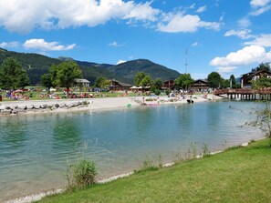 Een resort aan het meer met helder uitzicht op het water, een houten steiger en omliggende bergen.