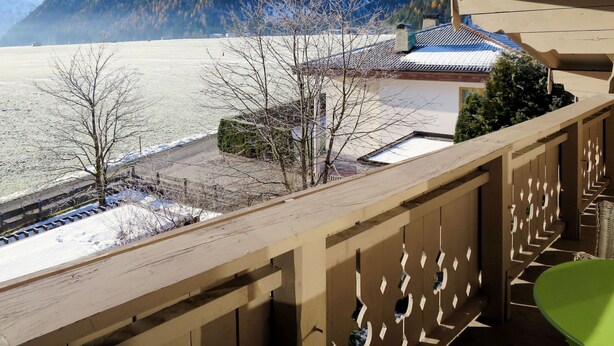 A balcony with a view of a snow-covered mountain and a traditional building with a tiled roof. - Apartment Rofan by Interhome (Achensee)