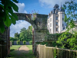 A historic building with a stone archway, a pathway, and a wooden fence.