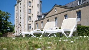 A building with a tower, two lounge chairs, and a clear sky. - Odalys Référence Le Château de Kéravéon by Interhome (Erdeven)