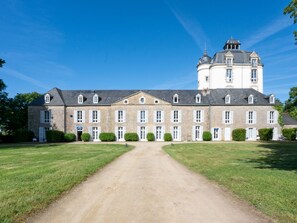 A large, historic building with a central courtyard, symmetrical windows, and a prominent tower.