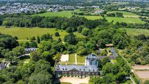 An aerial view of a large estate with a prominent building featuring a tower, surrounded by lush greenery and fields. - Odalys Référence Le Château de Kéravéon by Interhome (Erdeven)