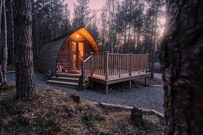 Eine Holzhütte mit einer Terrasse und einer Veranda, umgeben von Bäumen.